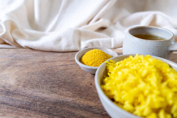 Landscape view of healthy turmeric powder with yellow rice and tea on ceramic ware
