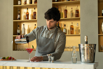 Bartender pouring Cosmopolitan cocktail in martini glass