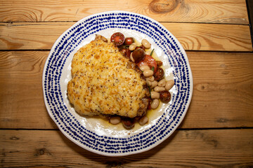 A delicious plate of a Rarebit pork chop with summer bean salad on a wooden kitchen table