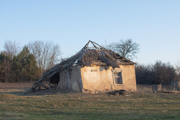 A ruined, dilapidated clay house - the roof is destroyed, the walls are destroyed.
