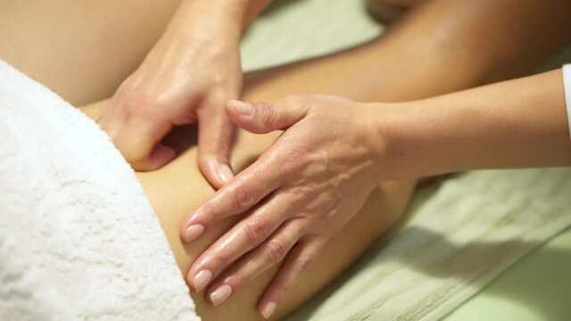 Decontracting leg massage, given by a masseuse woman. Hands giving relief to a tight muscle in an athlete, trigger point, contracture