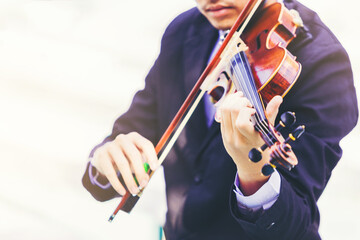 Fototapeta premium A musician man is practicing the violin playing with the melodiousness on bright background. Selected focus.