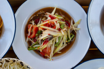 Papaya salad on bamboo table, famous Thai food, som tam, green papaya, street food. Lao Southeast Asia, Isan region of Thailand.