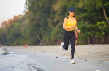 Asian female with yellow shirt running on the beach in the morning.