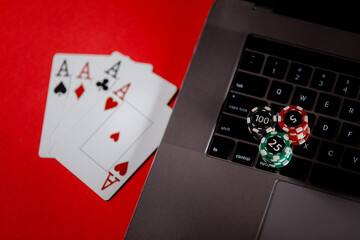 Poker cards, stacks of poker chips and laptop on a red background. Poker online concept