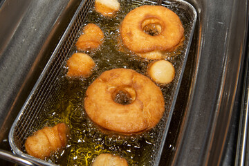 Delicious doughnuts and doughnut holes being cooked in a oil fryer showing the delicious snack...