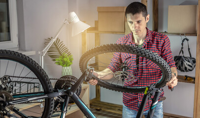Man is disassembling a mountain bike for maintenance. Concept of fixing and preparing the bicycle for the new season - obrazy, fototapety, plakaty