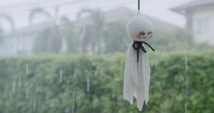 Handmade Cute Japan Doll Teru teru bouzu hanging against rainy day with natural background