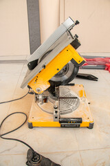 male hands of  construction worker sawing and cutting parts of  electric miter saw from  wooden board. wood board cutting process with blade rotation and dusty cloud electric miter saw