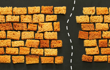 endless wall of rusks, slices of bread laid out like brickwork, passage in the wall with white dotted line road markings, seamless horizontal border pattern on black background, creative food