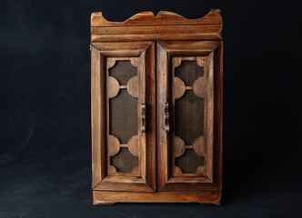 retro wardrobe box key keeper made of beige wood with bars on the doors patterns on a black background