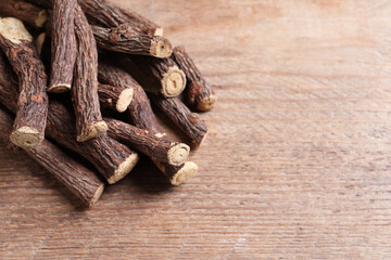 Dried sticks of liquorice root on wooden table, space for text