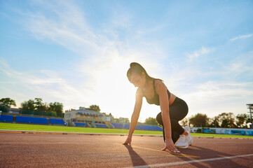 Young sport woman running at a track and field stadium
