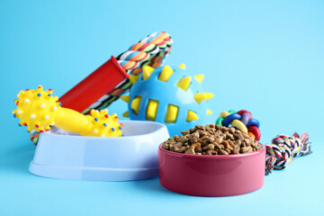 Feeding bowls and toys for pet on light blue  background