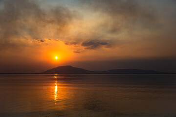 Beautiful landscape with mountain lake, reflection, golden sky and yellow sunlight in sunset. Thailand. Amazing scene.