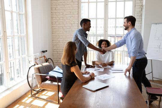 Smiling friendly male boss leader shaking hands with african american intern or employee, praising for good job or welcoming at first meeting. Two male mixed race colleagues establishing partnership