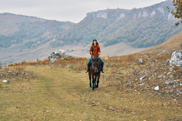 woman hiker in the mountains riding a horse adventure lifestyle