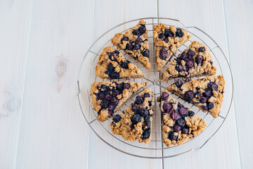 Freshly baked oat blueberry scones on cooling rack on white wooden background. Sweet food with natural ingredients. Vegan gluten free pastry..