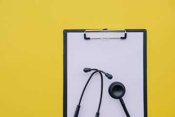 Black stethoscope and blank medical form on yellow background. Medicine and healthcare concept. Copy space. Flat-lay, top view.