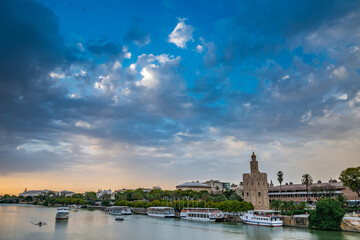 Obraz premium The Golden Tower (Torre del Oro) in Seville, Spain, is located at the margin of the Guadalquivir river and was built in the XIII century by the muslims ruling the area at the time.