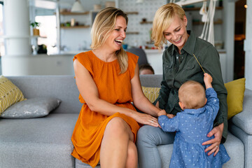 Happy lesbian female couple with her little child at home