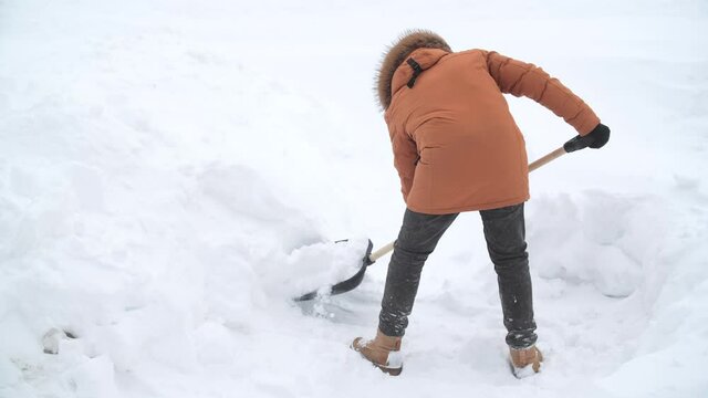 Aftermath of a blizzard. Man shovels snow in the yard in winter