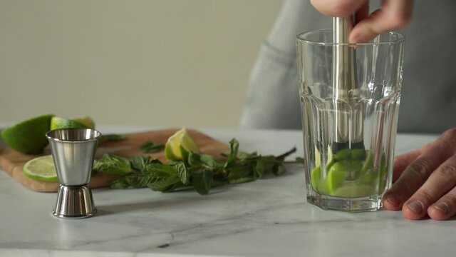 Bartender prepares a cocktail mojito using the madler. Bartender crushes mint and lime with a madler