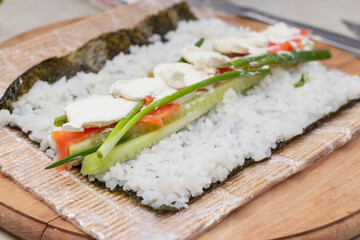 Cook's hands close-up. A chef makes sushi and rolls from rice, red fish, avocado and philadelphia cheese. step by step.