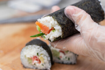 Cook's hands close-up. A chef makes sushi and rolls from rice, red fish, avocado and philadelphia cheese. step by step.
