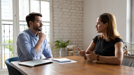 Professional male employer leader holding job interview with skilled female vacancy candidate, discussing working issues or previous experience. Thoughtful 30s businessman negotiating with partner.