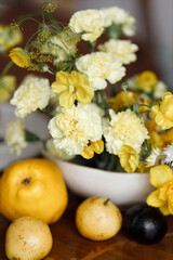A delicate composition with yellow flowers and fruits, with wedding invitations. Wedding decor in trendy shades, composition on the table with printing.
