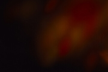 Blur colorful warm rainbow light leaks on black background with dust texture. Defocused abstract damaged scratched retro film analog effect for using over photos as overlay or screen filter