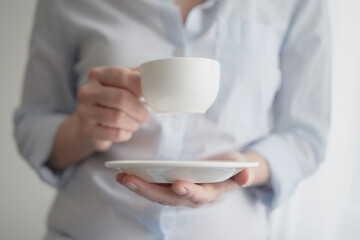 Cup of coffee tea plate in female hands on a gray gentle background