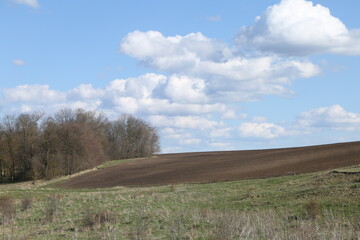 plowed field on the hill and clouds in the sky