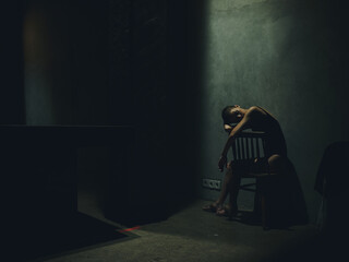 lonely woman sitting on a chair in a dark room and falling light silhouette depression