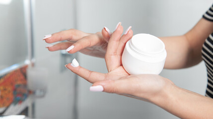 Female hands holding plastic jar of cream.