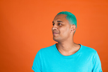 Black african man in casual on orange background blue hair happy positive smile looking left to empty space