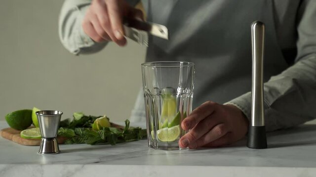 Bartender prepares a cocktail mojito using the madler. Bartender crushes mint and lime with a madler