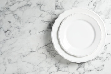 Empty ceramic plates on white marble table, top view. Space for text