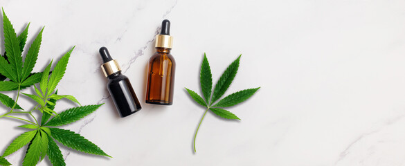 Organic Spa Cosmetic With Herbal cannabis ingredients. Serum with herbal extracts for skincare concept. Droppers with cannabis leafs on marble background. Top view, flat lay, banner