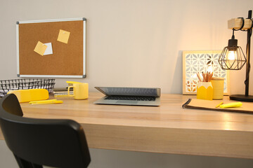 Naklejka premium Stylish workplace with laptop on wooden desk near light wall. Interior design