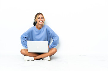 Young blonde Uruguayan girl with the laptop isolated on white background posing with arms at hip and smiling