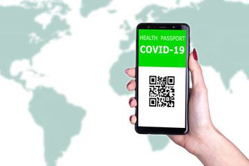 Female hand holding  new immunity covid-19 health passport on world background. Documents needed to journey after being vaccinated. Documented vaccine administration against coronavirus to fly safe.