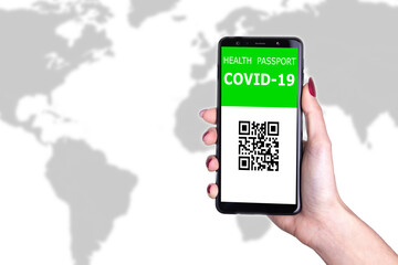 Female hand holding  new immunity covid-19 health passport on world background. Documents needed to journey after being vaccinated. Documented vaccine administration against coronavirus to fly safe.