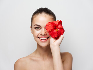 Fototapeta na wymiar cheerful woman with red flower bared shoulder cropped view