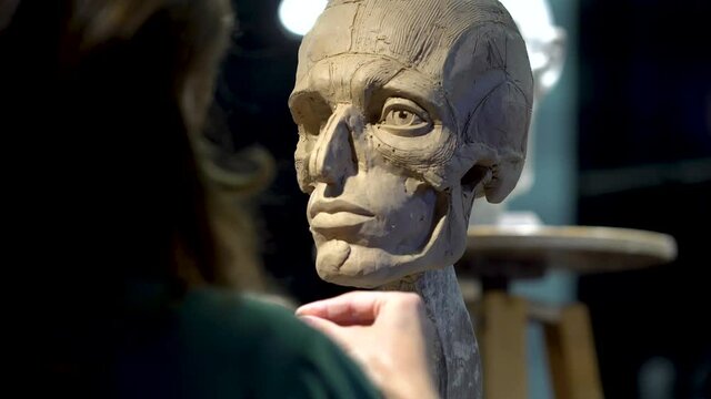 Woman sculptor at work on a sculpture of a human head.