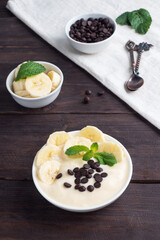 Healthy breakfast, dessert with milk yogurt banana and chocolate on a plate. Dark wooden background.