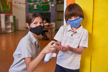 Erzieherin und Kind beim Hände desinfizieren