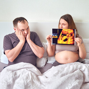 Shocked and excited husband next to pregnant wife and ultrasound results