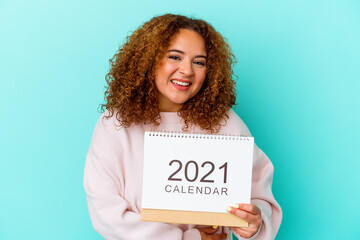 Young latin woman holding a calendary isolated on blue background laughing and having fun.